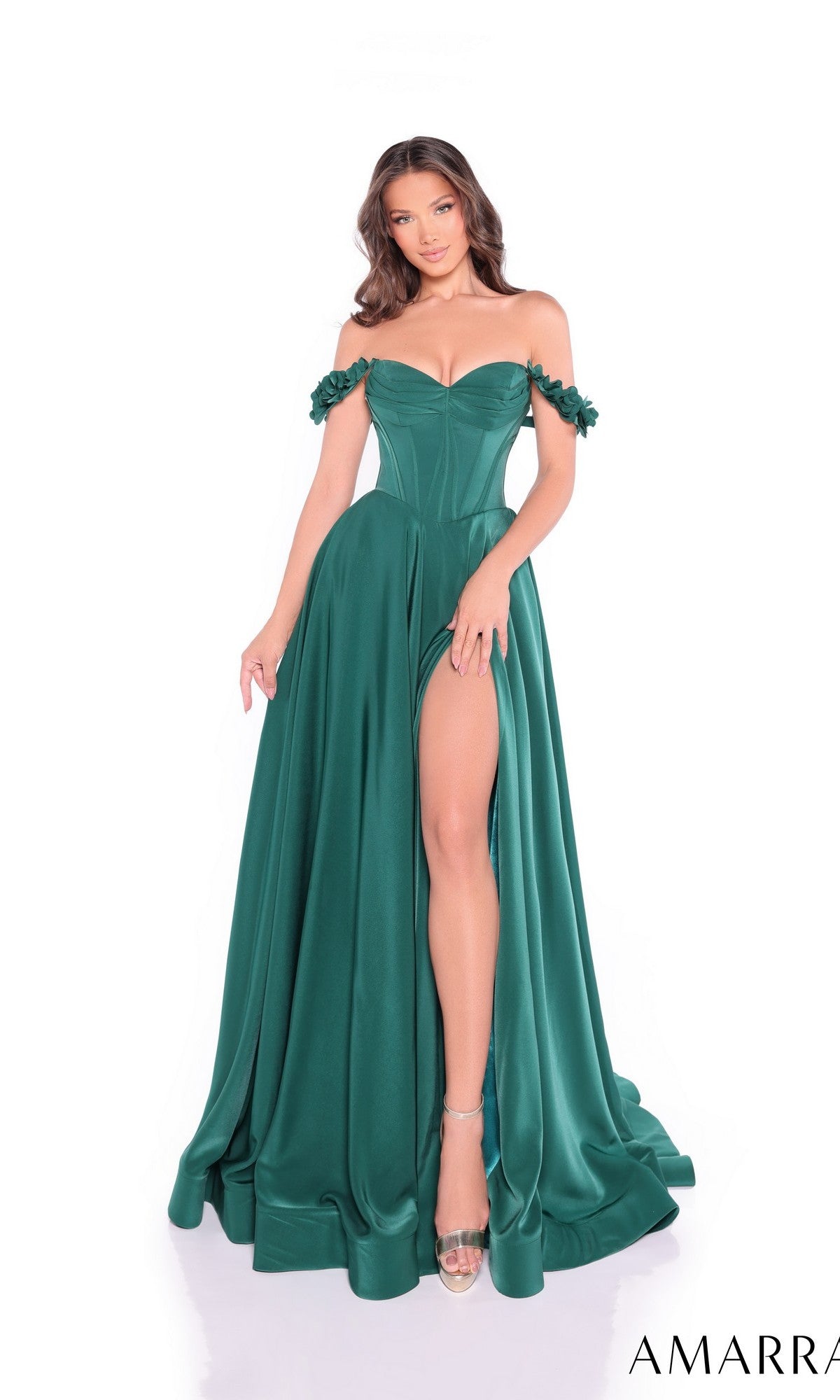 A woman models the Amarra 89441, a long emerald green satin prom dress with an off-the-shoulder corset bodice, floral straps, and high slit, standing against a white background.